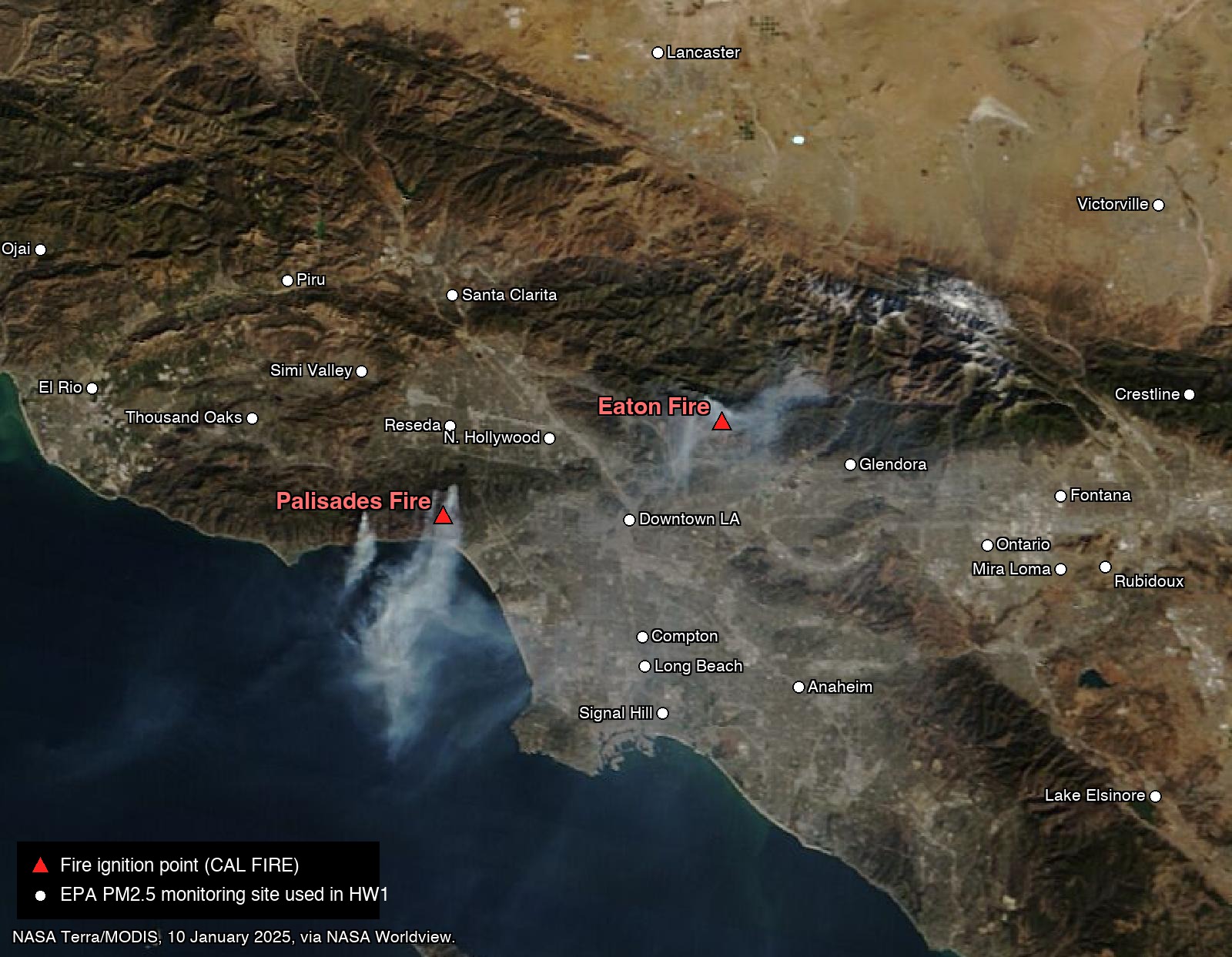 Satellite image of the Los Angeles basin on 10 January 2025. Two smoke plumes: the Palisades plume streaming from the coast out over the Pacific, and the Eaton plume drifting from the foothills over the basin. Red triangles mark the two ignition points; white circles with labels mark twenty-two air quality monitoring sites from Ojai and Lancaster in the north to Signal Hill and Lake Elsinore in the south.